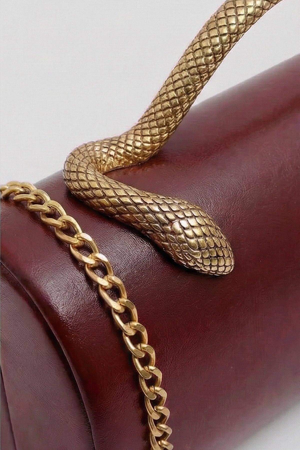 Bolso de Mano Estructurado con Asa de Serpiente y Cadena Dorada – Burdeos